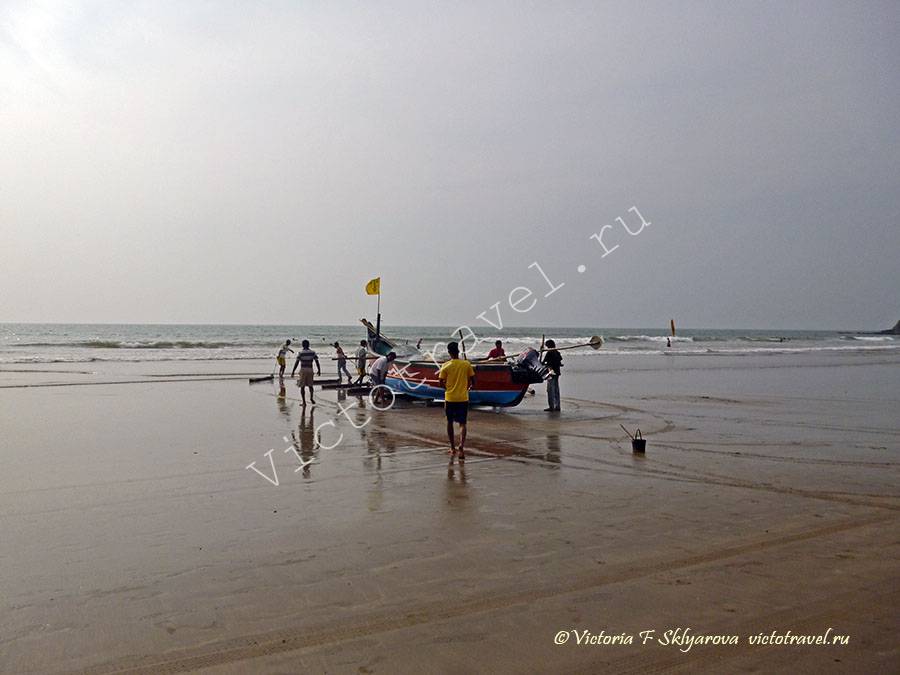 мужчины заносят лодку в море, пляж, Арамболь, Гоа, Индия